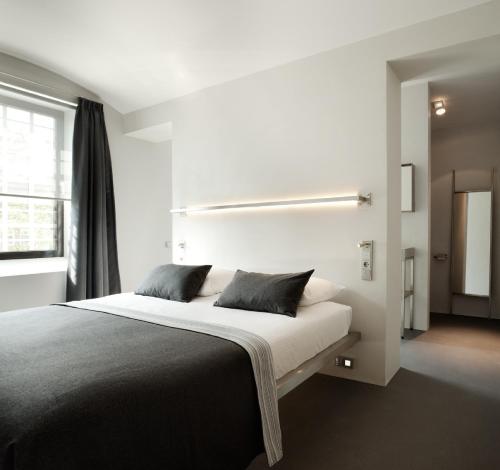 a white bedroom with a large bed with two pillows at Het Arresthuis in Roermond
