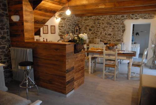 una cucina e una sala da pranzo con pareti in legno e tavolo di Chalet in pietra e legno con caminetto a Inverso Pinasca