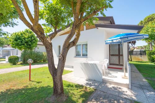 a white house with a tree and an umbrella at Margherita Family Apartments in Cavallino-Treporti