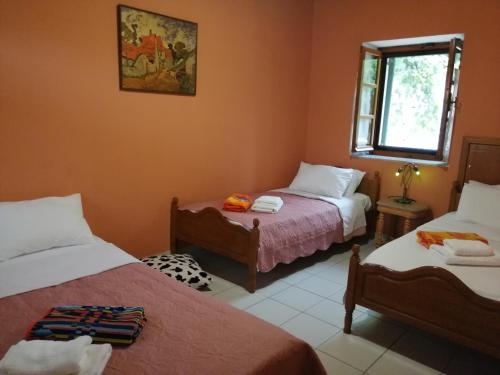 Un dormitorio con dos camas y una ventana. en Rodomelo House - 3 Bedrooms, en Leonidio