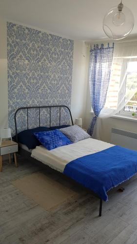 a bed in a bedroom with a blue wall at Apartament Baltic Relax in Rowy