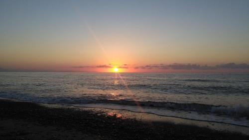 a sunset on the beach with the ocean at Xenia House in Lascari