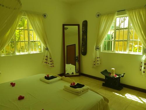 a bedroom with a large bed with green walls and windows at Mandinka Lodge in Kololi