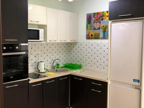 a kitchen with white cabinets and a black refrigerator at Apartments Dubrava 106 in Dobra Voda