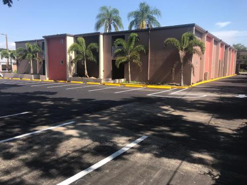 an empty parking lot with a building and palm trees at Tropical Inn & Suites, downtown clearwater in Clearwater