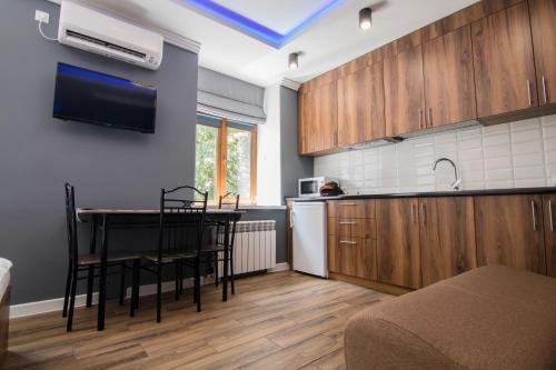 eine Küche mit Holzschränken sowie einem Tisch und Stühlen in der Unterkunft LUX Apartment near Arena City in Kiew