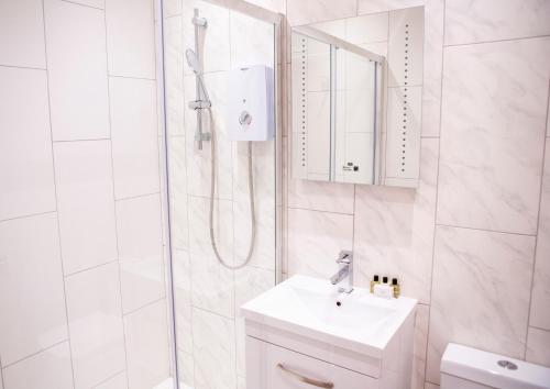 a white bathroom with a sink and a shower at Quiet Central West End Apartments by Indigo Flats in London