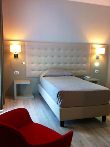 a bedroom with a bed and a red chair at Hotel San Francesco in Borgomanero