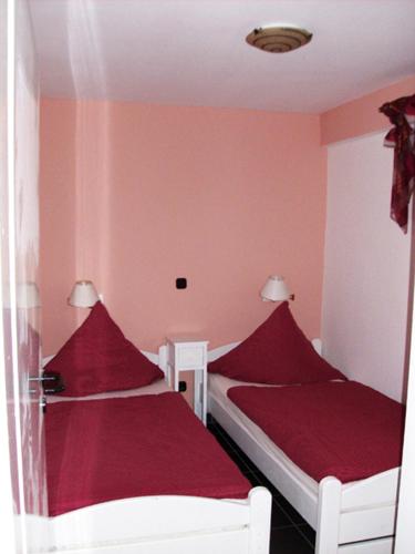 two beds in a small room with red sheets at Gästehaus Strandkonsulat in Scharbeutz
