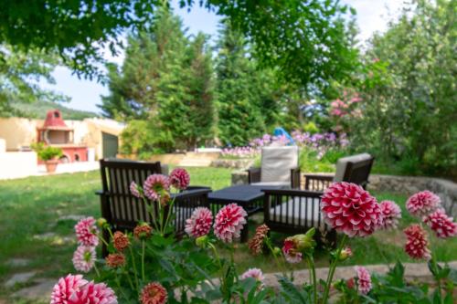 two chairs and a table in a garden with flowers at Villa Litsa in Ermones