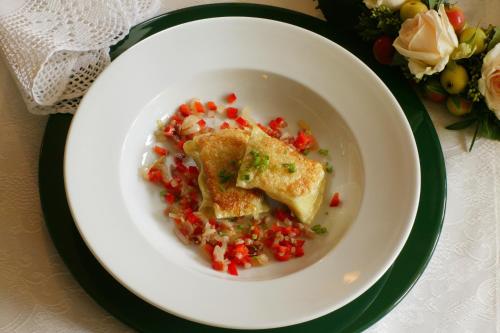 a white plate with a bowl of food on a table at Hotel Behringer's Traube in Badenweiler