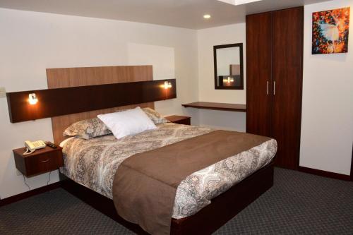 ein Hotelzimmer mit einem großen Bett und einem Spiegel in der Unterkunft Los Angeles Stay Inn in Quito