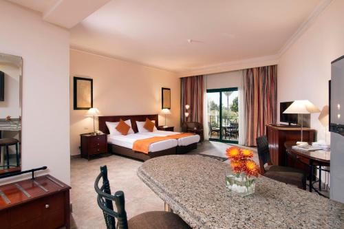 a hotel room with a bed and a table with flowers on it at Swiss Inn Plaza Hotel in 6th Of October