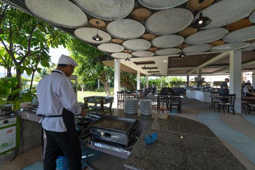 een man die voor een grill in een restaurant staat bij Blue Beach Grand Resort And Spa in Rawai Beach