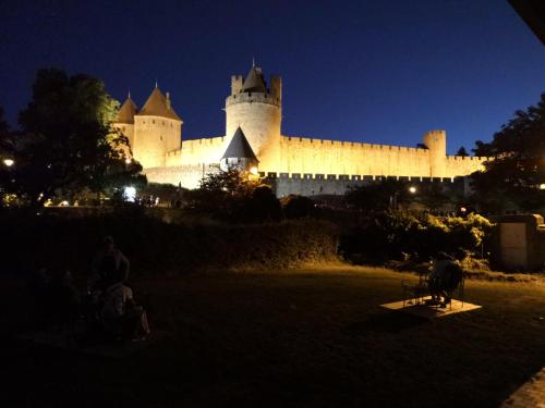 a person sitting on a bench in front of a large building at GOOD KNIGHT in Carcassonne