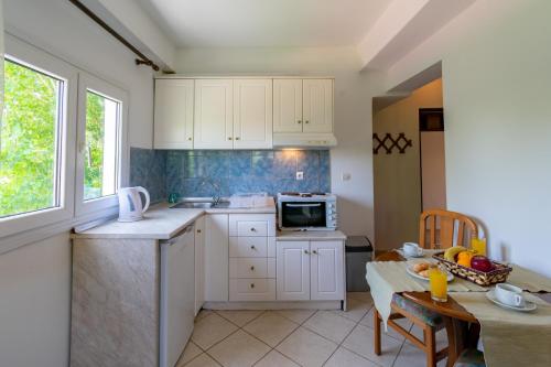 a kitchen with white cabinets and a table and a microwave at Villa Litsa in Ermones