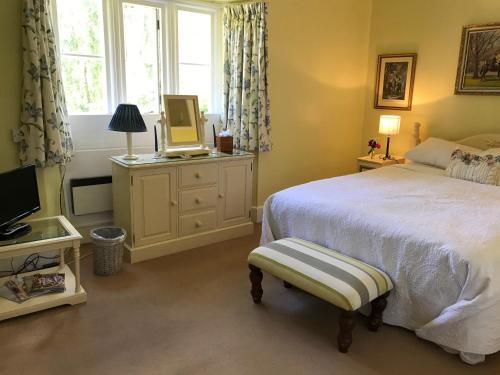a bedroom with a bed and a television and a window at The Manor Farm Alderton in Chippenham