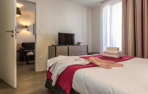 1 dormitorio con 1 cama con toallas en Odalys City Colmar La Rose d'Argent, en Colmar