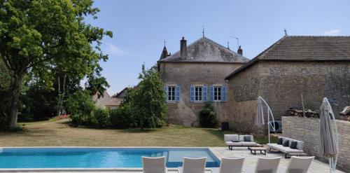 a pool in front of a house with chairs and a building at Manoir de Puyval in Rully