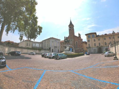 a parking lot with cars parked in front of a clock tower at Luna del Belvedere in Asti