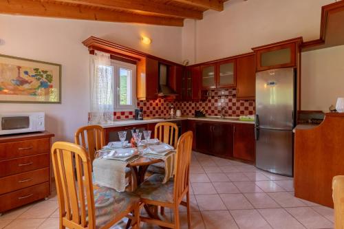 a kitchen with a table with chairs and a refrigerator at Villa Litsa in Ermones