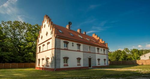 an old building with a roof on a grass field at Oficyna Krobielowice in Kąty Wrocławskie