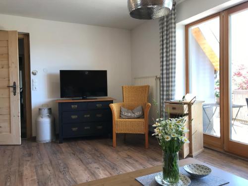 a living room with a television and a chair at Bei uns im Allgäu - Ferienwohnungen zum Wohlfühlen in Bad Wurzach