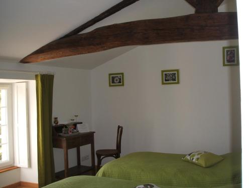 a bedroom with a green bed and a desk at Chambres d'hôtes La Charrière in Cheffois