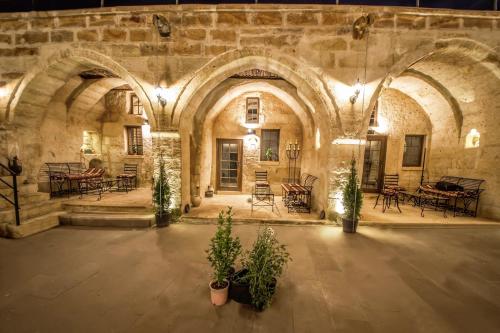 um antigo edifício de pedra com mesas, cadeiras e plantas em Harkasos Cave Hotel em Ürgüp