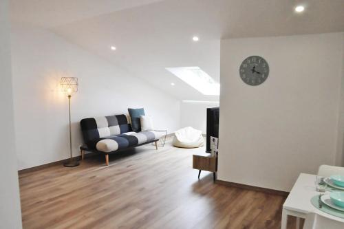 a living room with a couch and a clock on a wall at Loft acolhedor em Fátima perto do Santuário in Fátima