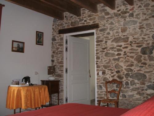 a bedroom with a stone wall with a table and a door at Chambres d'hôtes La Charrière in Cheffois