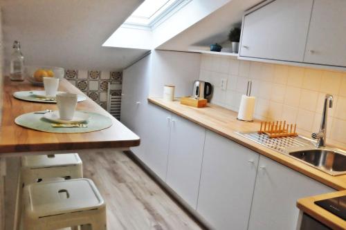 a kitchen with white cabinets and a sink and a counter at Loft acolhedor em Fátima perto do Santuário in Fátima