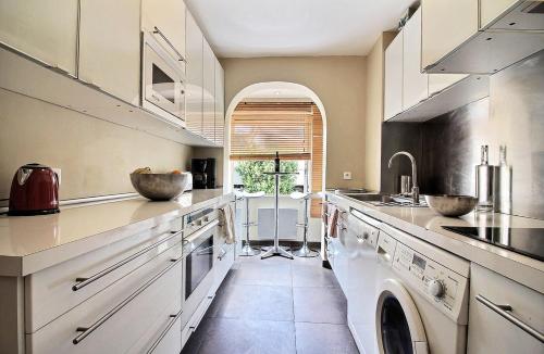 une grande cuisine avec des placards blancs et un évier dans l'établissement Leï Tapenié par Dodo-a-Cassis, à Cassis