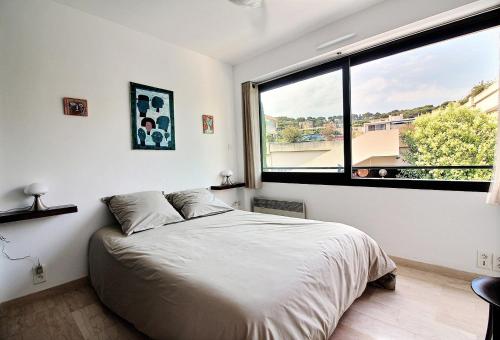 une chambre avec un lit et une grande fenêtre dans l'établissement Leï Tapenié par Dodo-a-Cassis, à Cassis