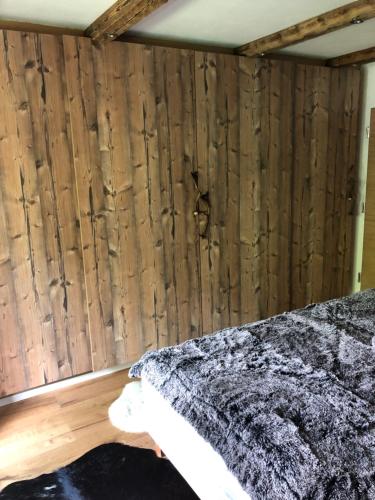 キルヒベルク・イン・チロルにあるKitzdesign in Kirchbergの木製の壁のベッドルーム1室、ベッド1台(毛布付)