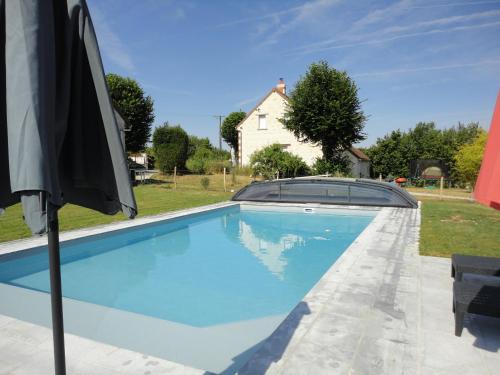 - une piscine avec un parasol à côté d'une maison dans l'établissement Le Hameau du Peu, à Châteauvieux