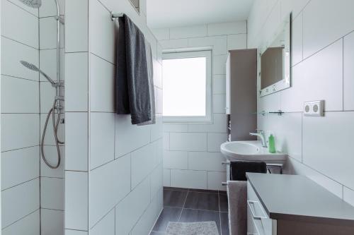 a white bathroom with a shower and a sink at Ferienwohnung Salzgrotte in Eggolsheim