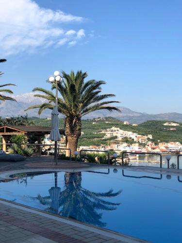 a swimming pool with a palm tree in the background at Apartment Sunkiss in Almirida