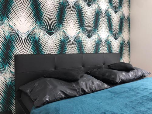 a bed with black pillows and a wall at 7th Heaven Apartments in Brno