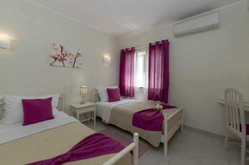 a bedroom with two beds and a window with purple curtains at Rocha Brava Village Resort in Carvoeiro