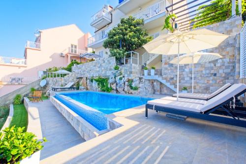 una imagen de una piscina con sombrilla y un edificio en Apartments Stella Maris, en Cavtat
