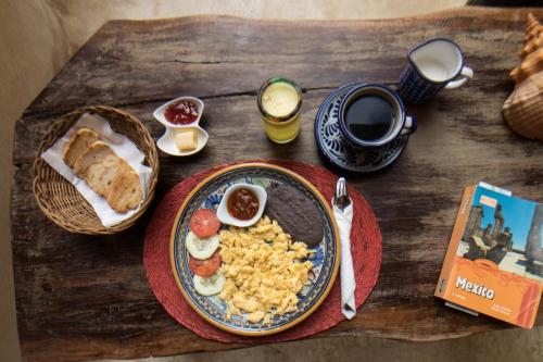 un tavolo in legno con un piatto di cibo e un libro di La Posada del Sol Boutique Hotel Tulum a Tulum