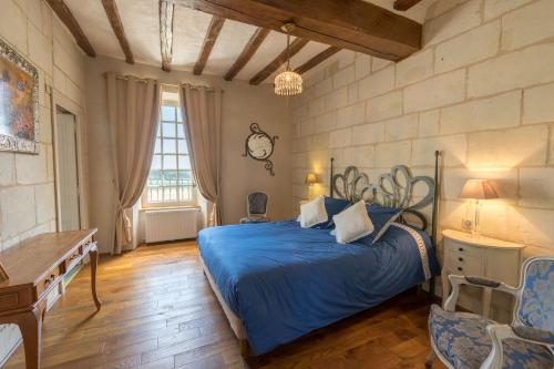 a bedroom with a blue bed and a wooden floor at La Gentilhommiere in Lerné
