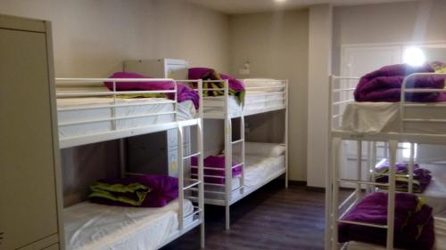 a room with three bunk beds with purple blankets at Hostel Catedral Burgos in Burgos