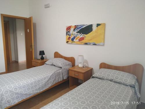 een slaapkamer met 2 bedden en een schilderij aan de muur bij Santa e Maria Affittacamere in Lamezia Terme