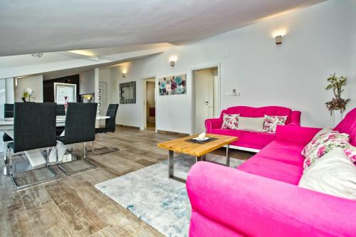 a living room with a pink couch and a table at Apartments Bubalo in Hvar