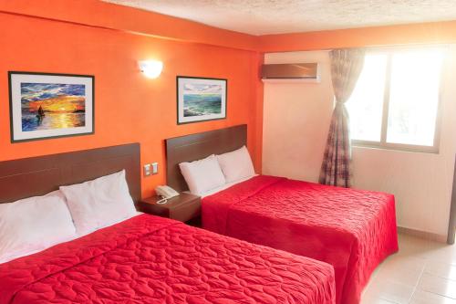 2 Betten in einem Hotelzimmer mit orangefarbenen Wänden in der Unterkunft Hotel ROLOVI in Veracruz