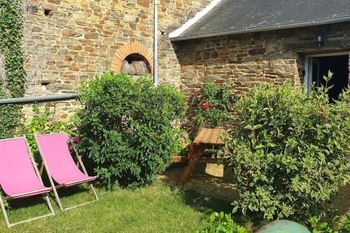 two pink chairs and a table in a garden at La clef des champs 3 in Meillac