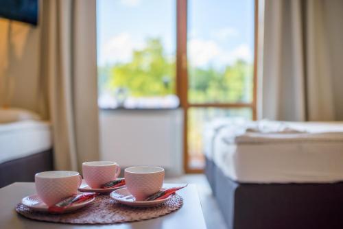 two cups and saucers on a table in a hotel room at Przystań Przy Lesie in Jantar