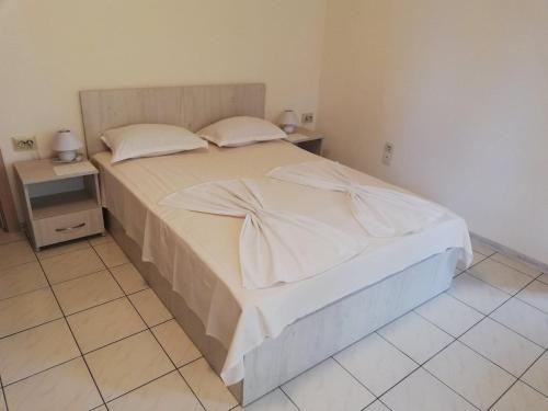 a bedroom with a bed with white sheets and pillows at Guest House Dimovi in Sozopol